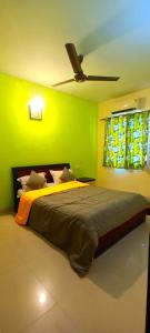 a bedroom with a large bed with a green wall at 2 BHK resort apat with Pool Near Candolim Beach AC WIFI in Goa