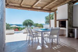 a table and chairs on a patio with a fireplace at Ananas villa Porto Pozzo in Porto Pozzo