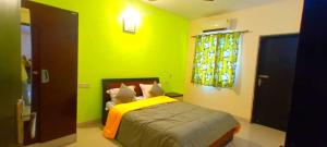 a bedroom with a bed with yellow walls and a window at 2 BHK resort apat with Pool Near Candolim Beach AC WIFI in Goa +9 photos