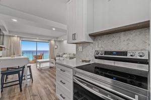 a kitchen with a stove top oven next to a living room at Summit 803 - Luxury Beach Resort Condo 1-6 People in Panama City Beach