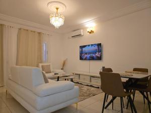 a living room with a white couch and a tv on the wall at Résidence-MDKM in Abidjan