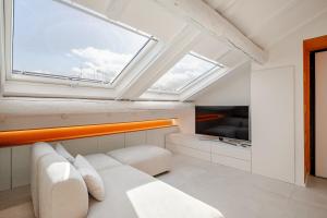 een woonkamer met een witte bank en een raam bij La Mansarda di Via Niella in Savona