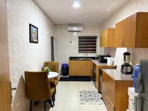 a kitchen with wooden cabinets and a table and chairs at Luxury 2-bed w 24h light in Magodo GRA Phase 2 in Sagisa