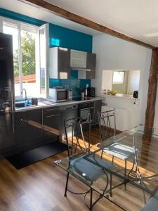 a kitchen with a glass table and some chairs at Le patio naturel in Saint-Étienne