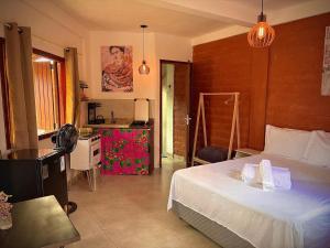 Un dormitorio con una cama blanca y una cocina. en Vila Kuir Hospedagens, en Alto Paraíso de Goiás