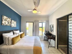 a bedroom with a bed with a ceiling fan and a desk at Beach Paradise in Ballito
