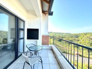 a balcony with a table and chairs and a television at Blissnest in Ballito