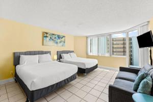 a hotel room with two beds and a couch at Top Of The Gulf 507 Beach Front Resort Ocean View in Panama City Beach