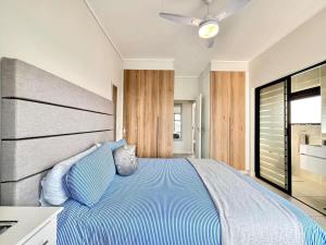 a bedroom with a bed with blue sheets and a ceiling at Shoreline Sanctuary! in Ballito