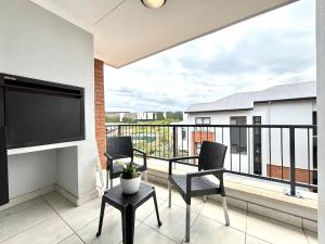 a balcony with two chairs and a flat screen tv at The Pearl in Ballito