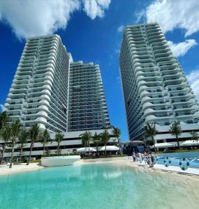 Dos edificios altos junto a una piscina con palmeras. en Azure North Pampanga Staycation, en San Fernando 14 fotos más