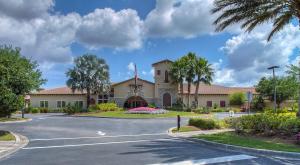 une route devant un bâtiment planté de palmiers dans l'établissement Second Floor River Strand Condo Overlooking the Golf Course - Sunny Life, à Marsh Island