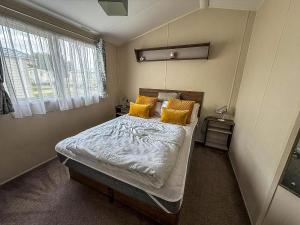 a small bedroom with a bed with yellow pillows at Caravan With Large Decking At Coopers Beach Holiday Park Ref 49012Sv in East Mersea +13 photos