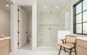 a bathroom with a shower and a toilet and a chair at Be A Nomad - Oceanview Luxe, 5BR Retreat in Jacksonville Beach