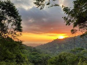 a sunset in the mountains with trees in the foreground at Stunning Oceanview Container House with Pool in Savegre