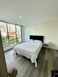 a white bedroom with a bed and two windows at Alamos Loft calle 14 in Pereira