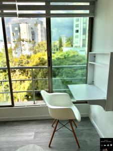 a white desk and chair in a room with a window at Alamos Loft calle 14 in Pereira