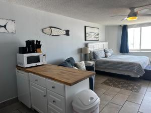 a room with a bed and a kitchen with a microwave at Beach Front Ocean View Condo - Top Of The Gulf 615 in Panama City Beach
