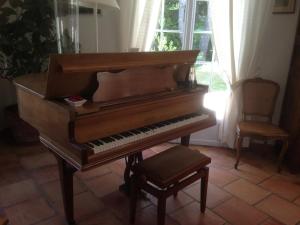 a piano in a room with a chair and a window at Villa élégante à Céreste avec piscine privée et jacuzzi in Céreste