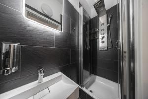 a black and white bathroom with a shower and a sink at Moderne Single Apartments Hauptbahnhof in Halle an der Saale
