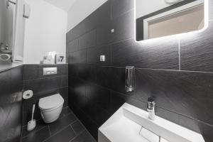 a black and white bathroom with a toilet and a sink at Moderne Single Apartments Hauptbahnhof in Halle an der Saale