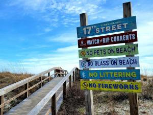 Un cartel en una pasarela de madera junto a una playa. en Sandpiper Condos by Tybee Vacation Rentals, en Tybee Island