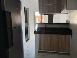 a kitchen with a black counter and a refrigerator at Espaço Marques in Porto Seguro