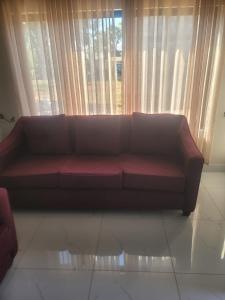 a brown couch sitting in a living room with a window at Tou Safari Lodge in Livingstone
