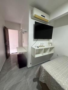 a bedroom with a bed and a flat screen tv at Suite aconchego Belém in Una