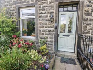 a brick house with a white door and flowers at Centenary Cottage in Skipton