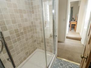 a shower with a glass door in a bathroom at Centenary Cottage in Skipton +15 photos