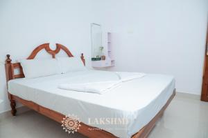 una camera da letto con un letto grande con lenzuola bianche di Lakshmi Ayurveda & Yoga Apartment a Kovalam Altre 10 foto