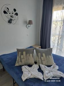 a bed with blue sheets and pillows with bows at Charmant petit appartement a Disneyland ! in Serris +30 photos