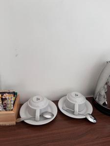 zwei weiße Teller und Löffel auf einem Holztisch in der Unterkunft Tongkonan Homestay Labuan Bajo in Komodo Labuan Bajo Airport