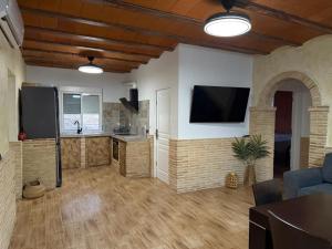 Il comprend un salon avec une cuisine et une télévision murale. dans l'établissement Casa Rural El Jardín De Sara, à Albudeite