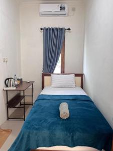 ein Schlafzimmer mit Bett, Schreibtisch und Fenster in der Unterkunft Tongkonan Homestay Labuan Bajo in Komodo Labuan Bajo Airport