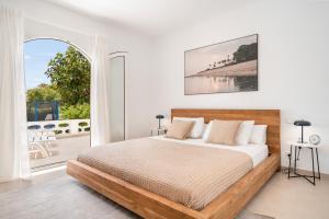 a white bedroom with a bed and a large window at Melodie home Menorca in Sa Caleta +18 photos