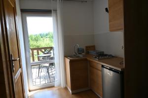 a kitchen with a sink and a view of a balcony at Pokoje Gościnne Przy Lesie in Pobiedna