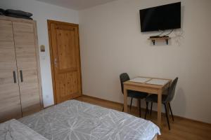 a bedroom with a bed and a table and a television at Pokoje Gościnne Przy Lesie in Pobiedna