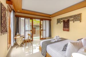 a bedroom with a bed and a desk and a window at Poset Unique Inn in Ubud