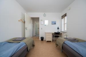 two beds in a room with a desk and a bedroom at Ilulissat Stay - Nanna's Vila - 2 in Ilulissat
