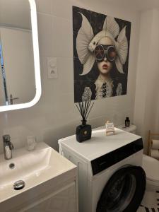 une salle de bains avec une peinture d'une femme portant des lunettes de soleil dans l'établissement La cour d Anvers, à Dieppe