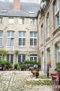 un grand bâtiment en briques avec des fenêtres, des tables et des chaises dans l'établissement La cour d Anvers, à Dieppe 49 autres photos