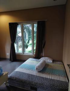 a bedroom with a bed with a large window at Guest House Sentul by Benchmark in Citaringgul 1
