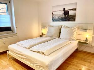 a bedroom with a white bed with a horse painting on the wall at Lichtblick Dähre in Dähre