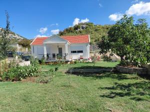 a small white house with a tree in a yard at Eco-Apartment Ostros Skutarisee in Ćurjan