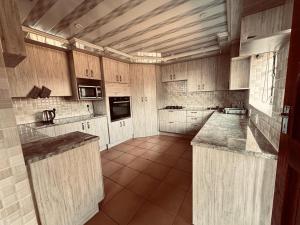 cocina grande con armarios de madera y encimeras de granito en Impala Game Ranch, en Dinokeng Game Reserve