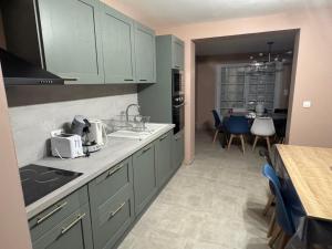 a kitchen with green cabinets and a table with chairs at Gite accueillant et confortable in Etreux