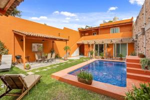 an orange house with a swimming pool in the yard at Riberas Suites in Chapala
