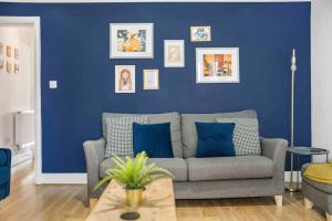 a living room with a couch and a blue wall at GuestReady - Charming Retreat in Trafford in Manchester